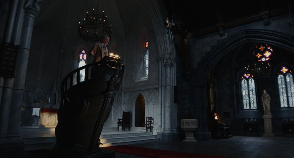 An image of Benoit Blanc speaking on the church pulpit.