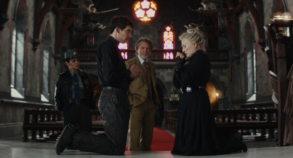 An image of Martha kneeling and preparing to confess before Father Jud, observed by Blanc and Geraldine.