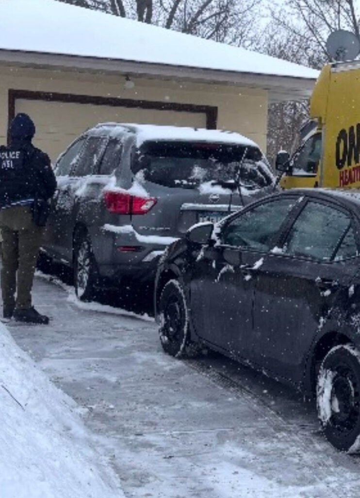 Photo of an ICE agent looming at a woman’s front door, hunting for people branded as ‘unwanted’ workers.